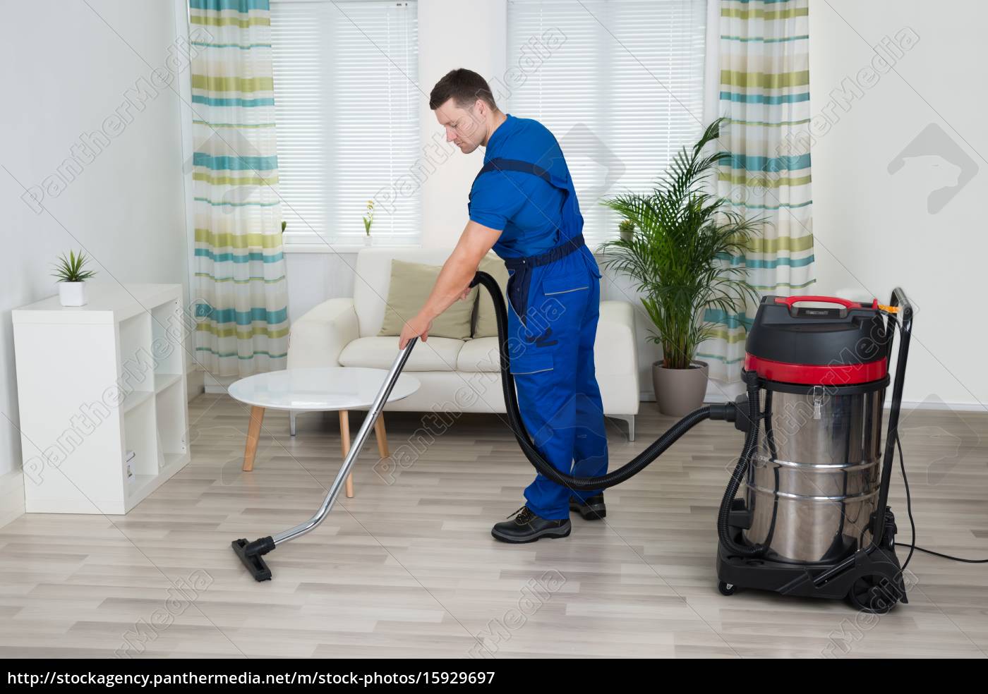 Maschio Lavoratore Pulizia Divano Con aspirapolvere - Stockphoto