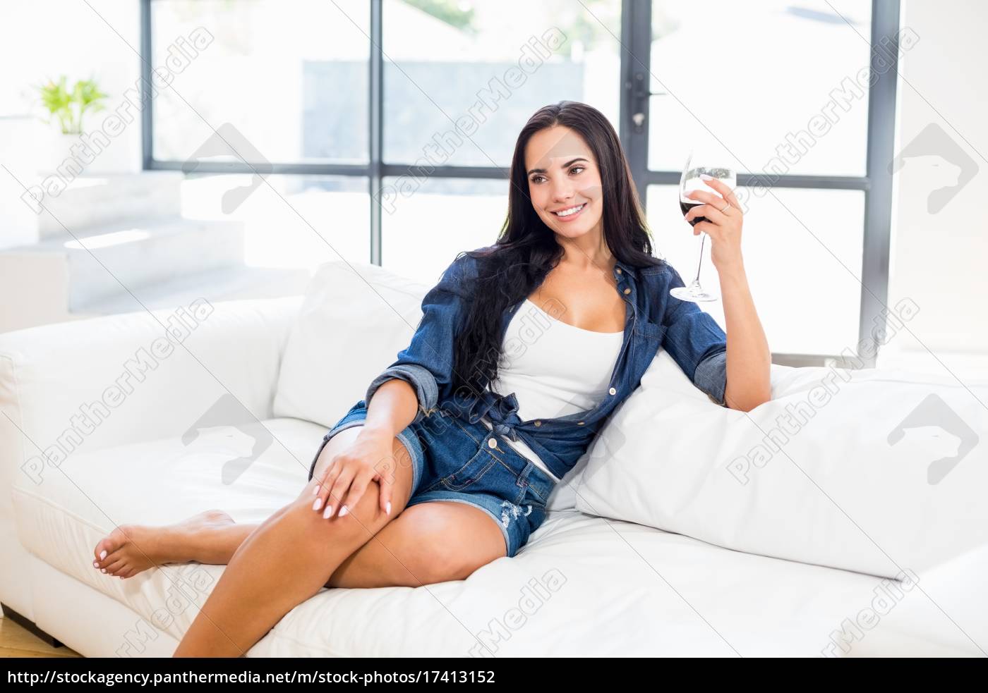 donna seduta sul divano con un bicchiere di vino rosso - Stockphoto  #17413152