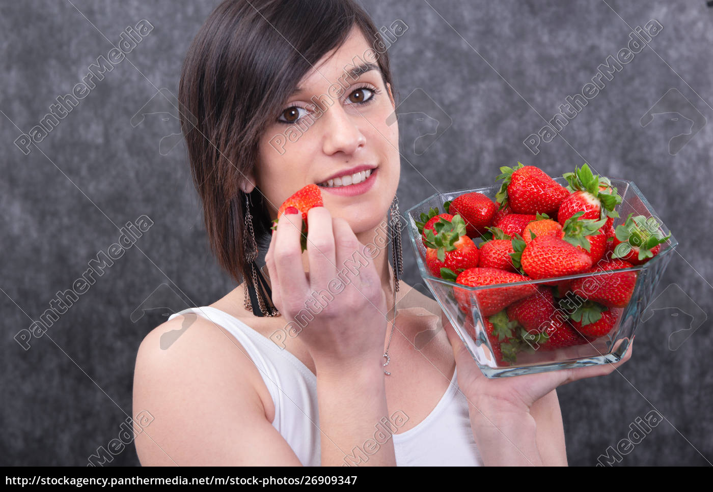 Giovane donna brunetta graziosa che mangia fragola - Foto stock #26909347